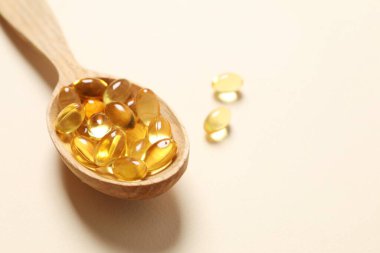 Omega-3 kapsüllerinin ahşap kaşığı mavi arka planda, kopyalanmış. Sağlık, refah ve takviyeler..