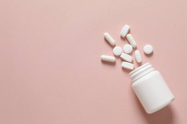 Renkli arka planda haplarla dolu bir şişe. 