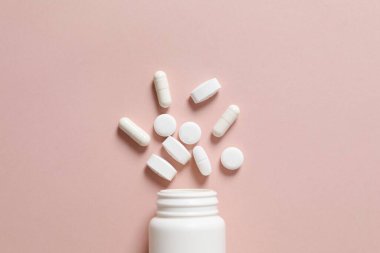 Renkli arka planda haplarla dolu bir şişe. 