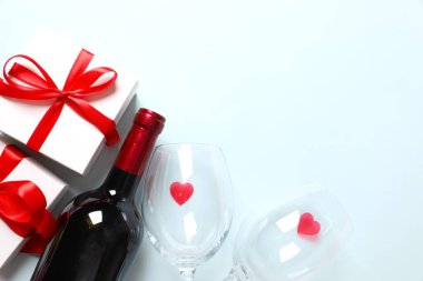 Sevgililer Günü yemeği konsepti. Romantik akşam yemeği, bir şişe şarap şampanyası, bardaklar, beyaz hediye kutusu, şekerler. Sevgililer günü kartı. Kopya alanı olan Sevgililer Günü afişi.