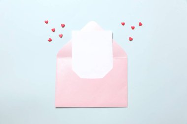 İçinde beyaz notlar olan pembe bir zarf ve pembe arka planda sevgililer günü kalpleri. Düz yerde, üst tarafta. Sevgililer Günü konsepti için romantik aşk mektubu.