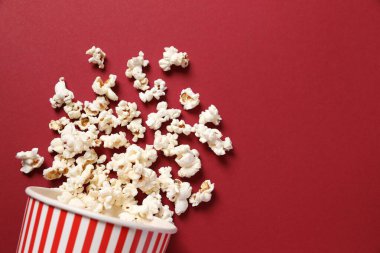 Çizgili karton kovada renkli bir arka planda nefis patlamış mısır.