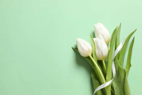 Beautiful white tulips on colored background