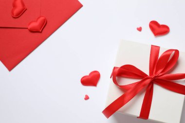 Kırmızı zarfta hediye ve pembe arka planda kırmızı kalpler. Düz yatış, üst görünüm