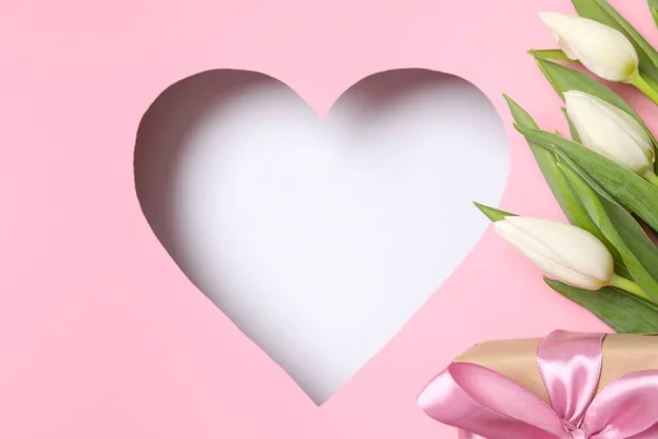 Heart with fresh tulips on pastel pink background
