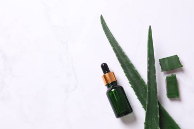 Gri arka planda taze aloe vera yapraklı düz kozmetik serumu. Organik kozmetik ürünleri. Üst görünüm düzlüğü, kopyalama alanı. Kozmetik, SPA markalaşması, maket.