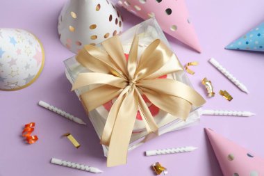 Renkli arka planda mumları ve şapkaları olan doğum günü pastası