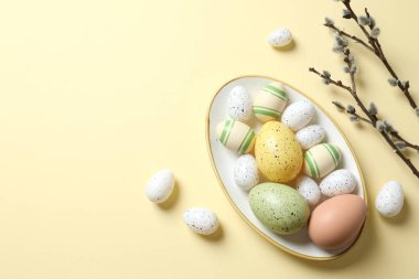 Paskalya dekoru konsepti. Pastel arka planda bir tabakta renkli yumurtaların en üstteki görüntüsü 