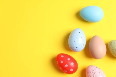 Paskalya dekoru konsepti. Sarı arkaplanda renkli yumurtaların üst görünüm fotoğrafı ve metin için boşluk