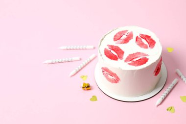 Renkli arka planda mumlarla süslenmiş kırmızı dudaklı renkli pasta