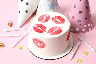 Kırmızı dudaklar ve mumlarla süslenmiş renkli pasta, renkli arka planda şapkalar