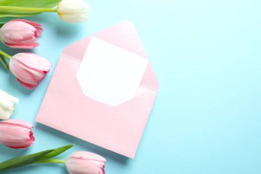 Kağıt kartlı açık pembe zarfın en üstteki resmi ve boş arkaplan üzerine lale çiçekleri.