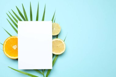 Beyaz kartla yazlık tropikal kompozisyon. Renkli arka planda yeşil yapraklar ve tropikal meyveler. Yaz kavramı. Düz konum, üst görünüm, kopyalama alanı