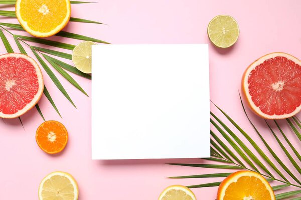 Summer tropical composition with a white card. Green palm leaves and tropical fruits on a colored background. Summer concept. Flat lay, top view, copy space
