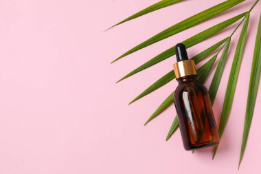 Kozmetik yüz serumuyla cilt bakımı. Renkli arka planda pipeti olan cam bir şişe. Kuru cilt bakımı ürünü. Vücudun derisini nemlendirmek için gerekli yağ..