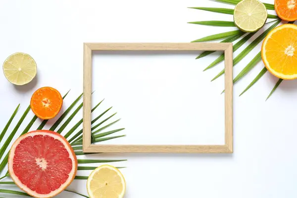Summer tropical composition with a wooden frame. Green palm leaves and tropical fruits on a white background. Summer concept. Flat lay, top view, copy space