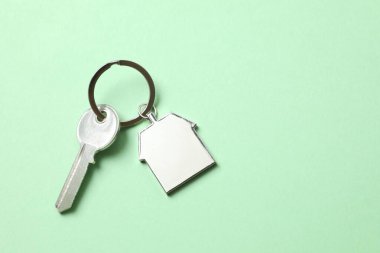 Renk arkaplan üzerinde ev şeklinde anahtarlığı olan metalik anahtar