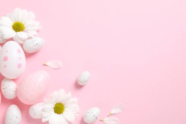 Paskalya yumurtaları ve çiçeklerle süslenmiş arka plan, üst görünüm