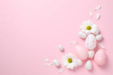 Paskalya yumurtaları ve çiçeklerle süslenmiş arka plan, üst görünüm