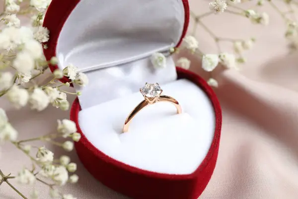 美丽的金光闪闪的订婚戒指 丝织品上镶嵌着巨大的钻石宝石 镶嵌在一个华丽的红色天鹅绒盒中 图库照片