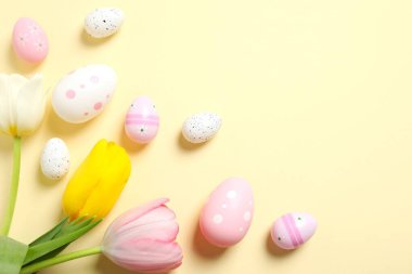 Paskalya dekoru konsepti. Renkli arka planda laleleri olan renkli yumurtaların üst görünüm fotoğrafı ve metin için boşluk
