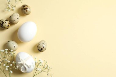 Bej arka planda Paskalya yumurtaları ve çiçek dallarıyla kompozisyon