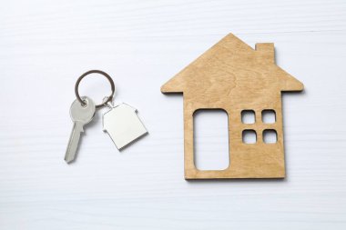 Anahtarlıklı metal anahtar ve beyaz arka planda ahşap ev