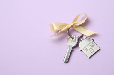 Metallic key with keychain on color background clipart