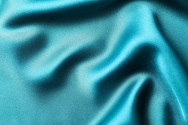İpek saten turkuaz rengi. Parlak pürüzsüz kumaş. Yumuşak kıvrımlar. Tasarım için alanı olan lüks bir arka plan. Düz masa, üst görünüm