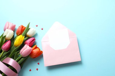 Kağıt kartlı açık pembe zarfın en üstteki resmi ve boş arkaplan üzerine lale çiçekleri.