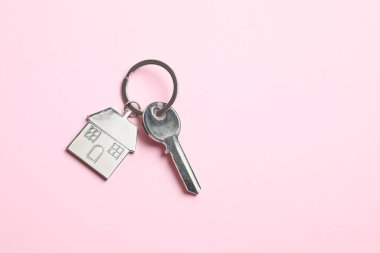 Renk arkaplan üzerinde ev şeklinde anahtarlığı olan metalik anahtar