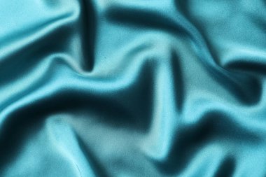 İpek saten turkuaz rengi. Parlak pürüzsüz kumaş. Yumuşak kıvrımlar. Tasarım için alanı olan lüks bir arka plan. Düz masa, üst görünüm