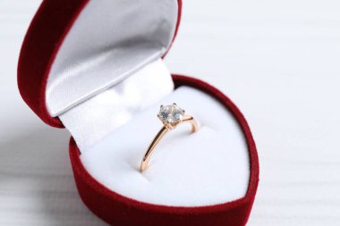 Zengin kırmızı kadife kutusunda büyük elmas mücevher olan güzel, parlak altın nişan yüzüğü. 