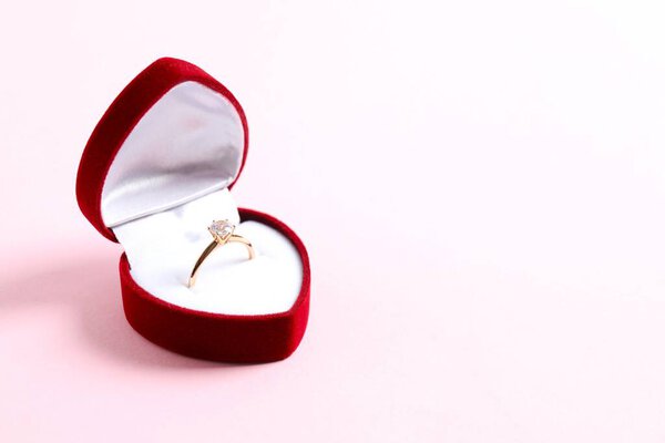 Beautiful shiny gold engagement ring with large diamond gemstone in rich red velvet box 