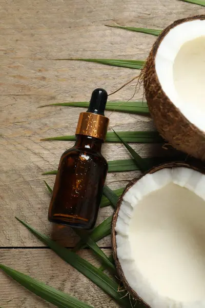 Skin care with facial serum. Glass bottle with pipette on a wooden background. Dry skin care product. Coconut essential oil moisturizing the skin of the body