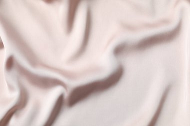 Bej ipek saten. Parlak pürüzsüz kumaş. Yumuşak kıvrımlar. Tasarım için alanı olan lüks bir arka plan. Düz masa, üst görünüm