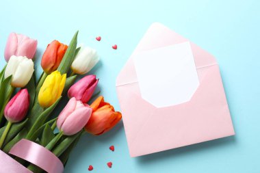 Kağıt kartlı açık pembe zarfın en üstteki resmi ve boş arkaplan üzerine lale çiçekleri.