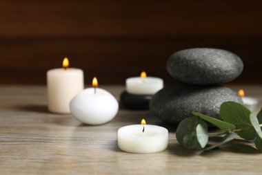 Beautiful composition with burning wax candles and eucalyptus on the table