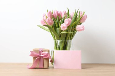 Anneler Günü konsepti. Vazodaki güzel lale buketi, masanın üzerinde bir kart olan hediye kutusu.