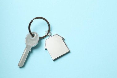 Renk arkaplan üzerinde ev şeklinde anahtarlığı olan metalik anahtar