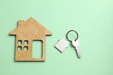 Anahtarlığı olan metal anahtar ve arka planda ahşap ev