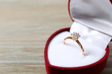 Zengin kırmızı kadife bir kutuda büyük elmas taşlı güzel, parlak altın bir nişan yüzüğü. 