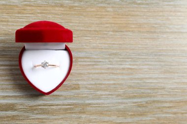 Zengin kırmızı kadife bir kutuda büyük elmas taşlı güzel, parlak altın bir nişan yüzüğü. 