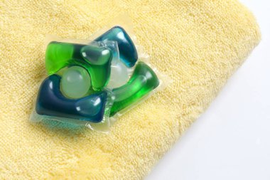 Havluda yıkama kapsülleri. Çamaşır makinesinde çamaşır yıkamak için sıvı tozlu kapsüller.. 