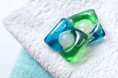 Havluda yıkama kapsülleri. Çamaşır makinesinde çamaşır yıkamak için sıvı tozlu kapsüller.. 