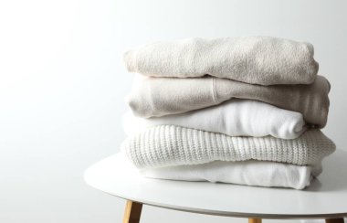 Bir yığın yeni yıkanmış, ahşap bir masanın üzerinde düzgünce katlanmış kıyafet.