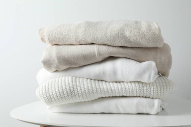 Bir yığın yeni yıkanmış, ahşap bir masanın üzerinde düzgünce katlanmış kıyafet.