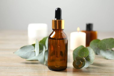 Okaliptüs, ahşap zemin üzerinde yeşil okaliptüs yaprakları olan cam bir şişede gerekli yağdır. Aromaterapi konsepti. Spa mı? Kozmetik ve vücut bakımı için doğal organik malzemeler.