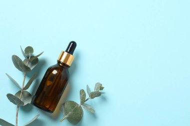 Okaliptüs, ahşap zemin üzerinde yeşil okaliptüs yaprakları olan cam bir şişede gerekli yağdır. Aromaterapi konsepti. Spa mı? Kozmetik ve vücut bakımı için doğal organik malzemeler.