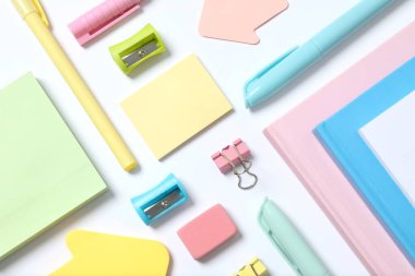 Renkli okul kırtasiyesi ve beyaz arkaplan üzerine not defteri ile düz yatıyordu, üst görünüm